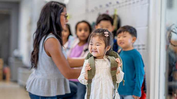 Teacher helping with students with their backpacks while leaving.