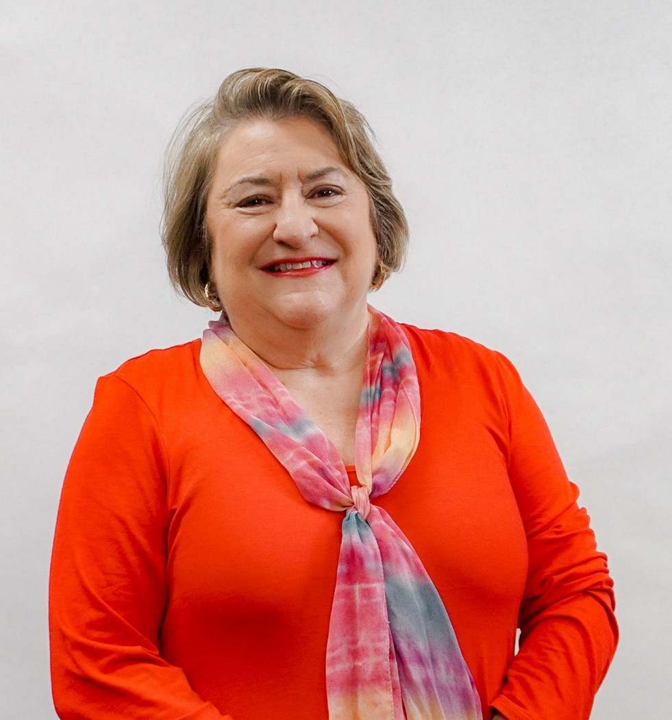 Maxine Todd in a red-orange blouse and multi-color scarf