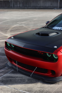 front end view of a muscle car painted red with a black matte finish hood