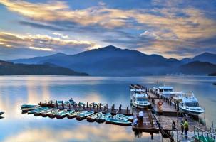 boats on a wooden dock at sunset with golden clouds and a moutainous bacground 