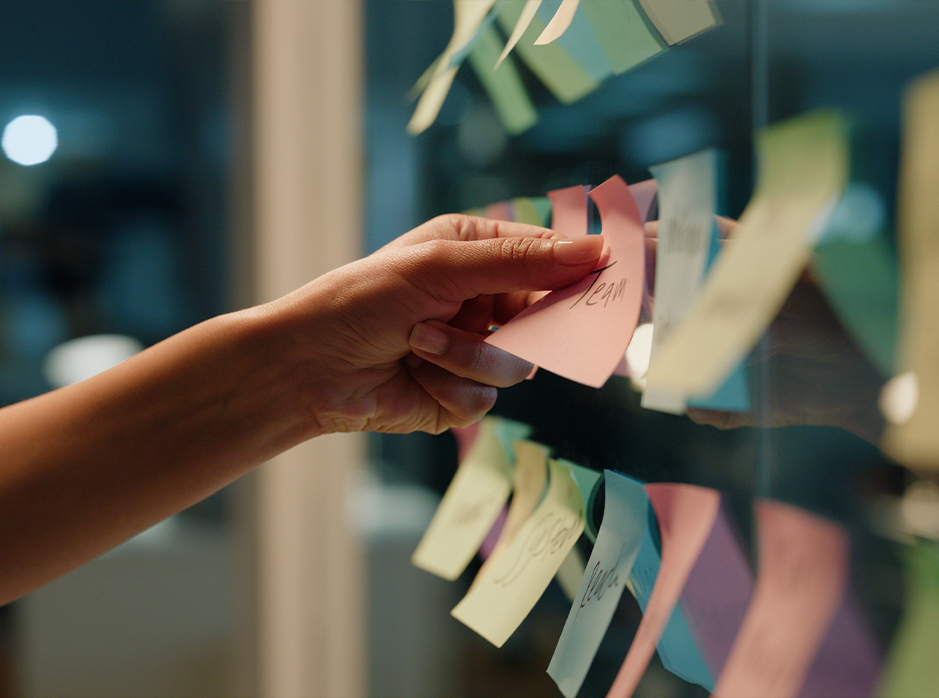 hand putting sticky notes on a window next to other sticky notes