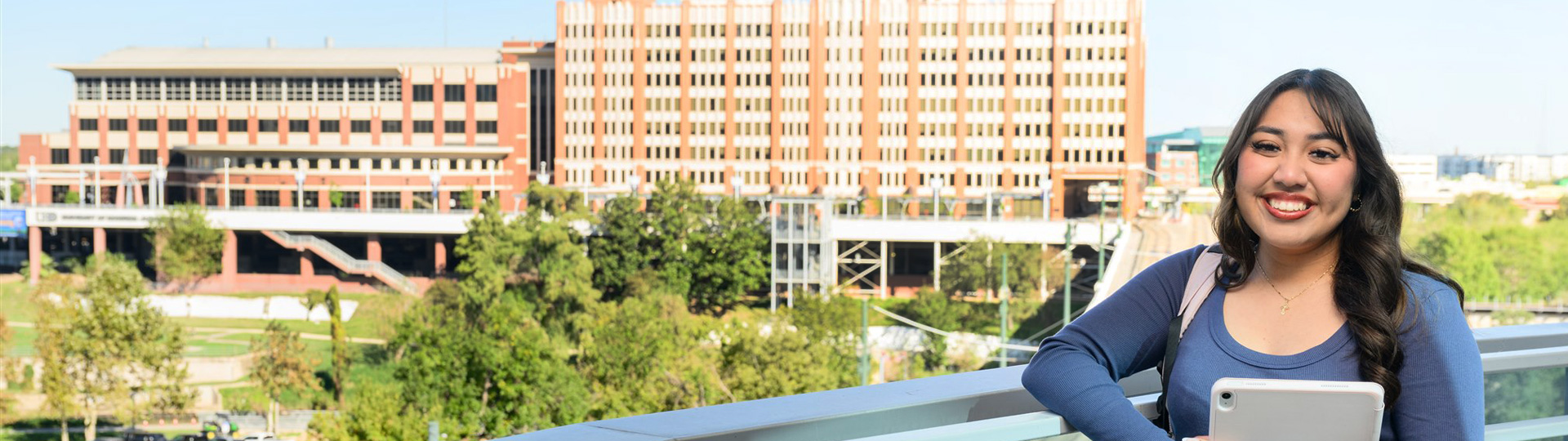 Smiling UHD female student with the One Main Building and  Academic Buuilding in the background