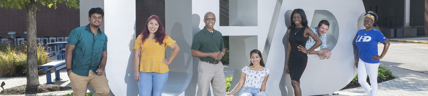 Group of students by the UHD logo.