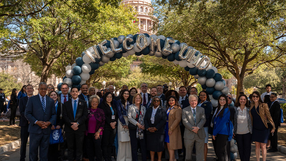 UHD Representatives under a balloon arch reading 'Welcome UHD,' the Texas capital building can be spotted in the background