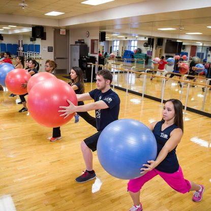 Students at the WSC taking an exercise class. They are lunging forward holding exercise balls in front of their bodies.