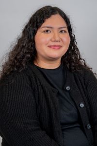 Gizelle Lopez poses for a headshot. She is wearing all black