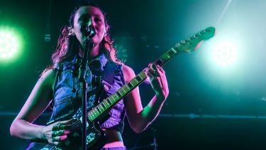 Luna Li plays guitar during a concert.