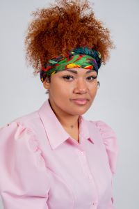 Selah Jones poses for a photo. Wearing a pink shirt and a colorful headband.