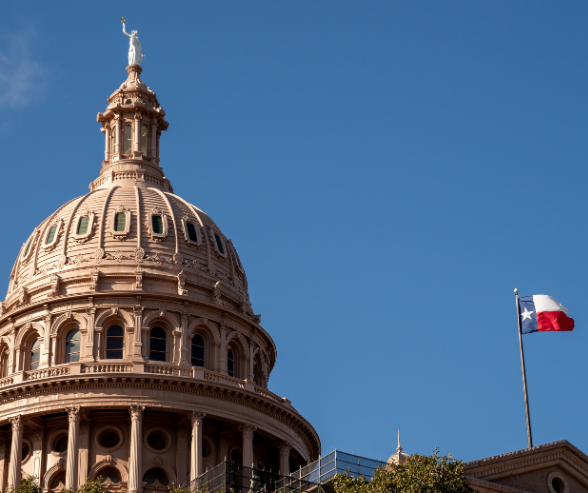 Texas Capitol building and Texas flag waving in the wind