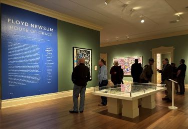 People standing inside the Floyd Newsum: House of Grace exhibit, viewing Newsum's art.