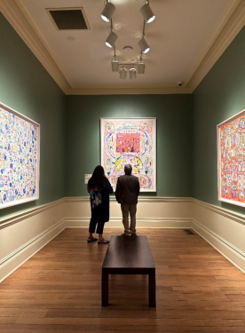 Two people stand viewing one of Newsum's paintings. Their backs are toward the camera.