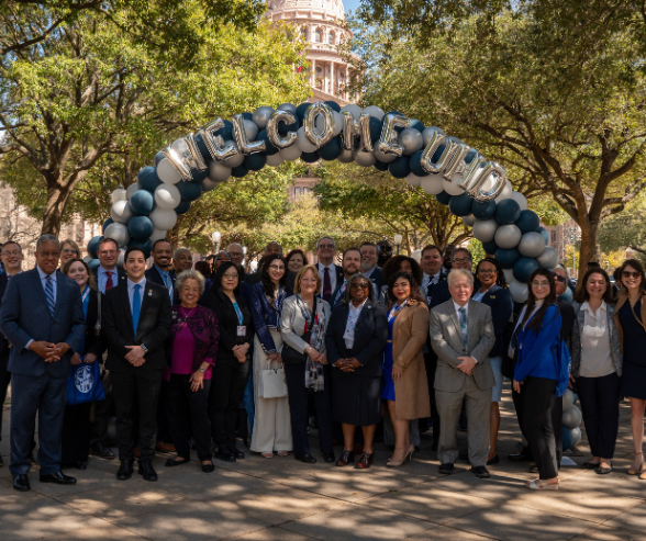 uhd staff and uhd president loren j blanchard stand aside a balloon arch with the words "Welcome UHD" outside the Texas Capitol in Austin, Texas