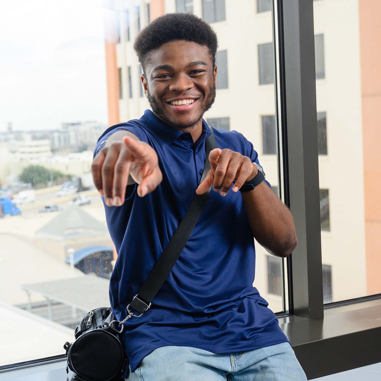 Male student smiling and pointing at you.