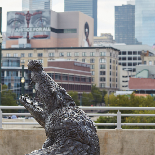 A gator statue on the University of Houston Downtown campus overloooking the Downtown Houston skyline.